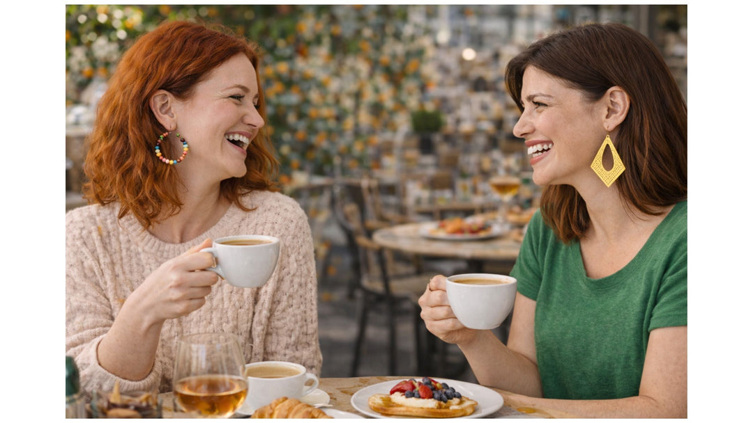 Lifestyle shot of two friends laughing at a café during Easter long weekend, styling vibrant colorful beaded hoops and yellow filigree drop statement earrings.