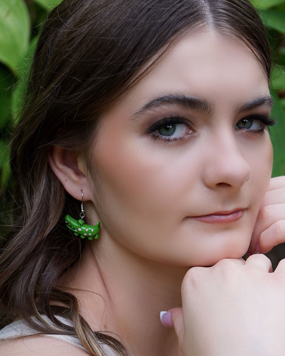 Side profile of model wearing cute green crocodile drop earrings with silver hooks.