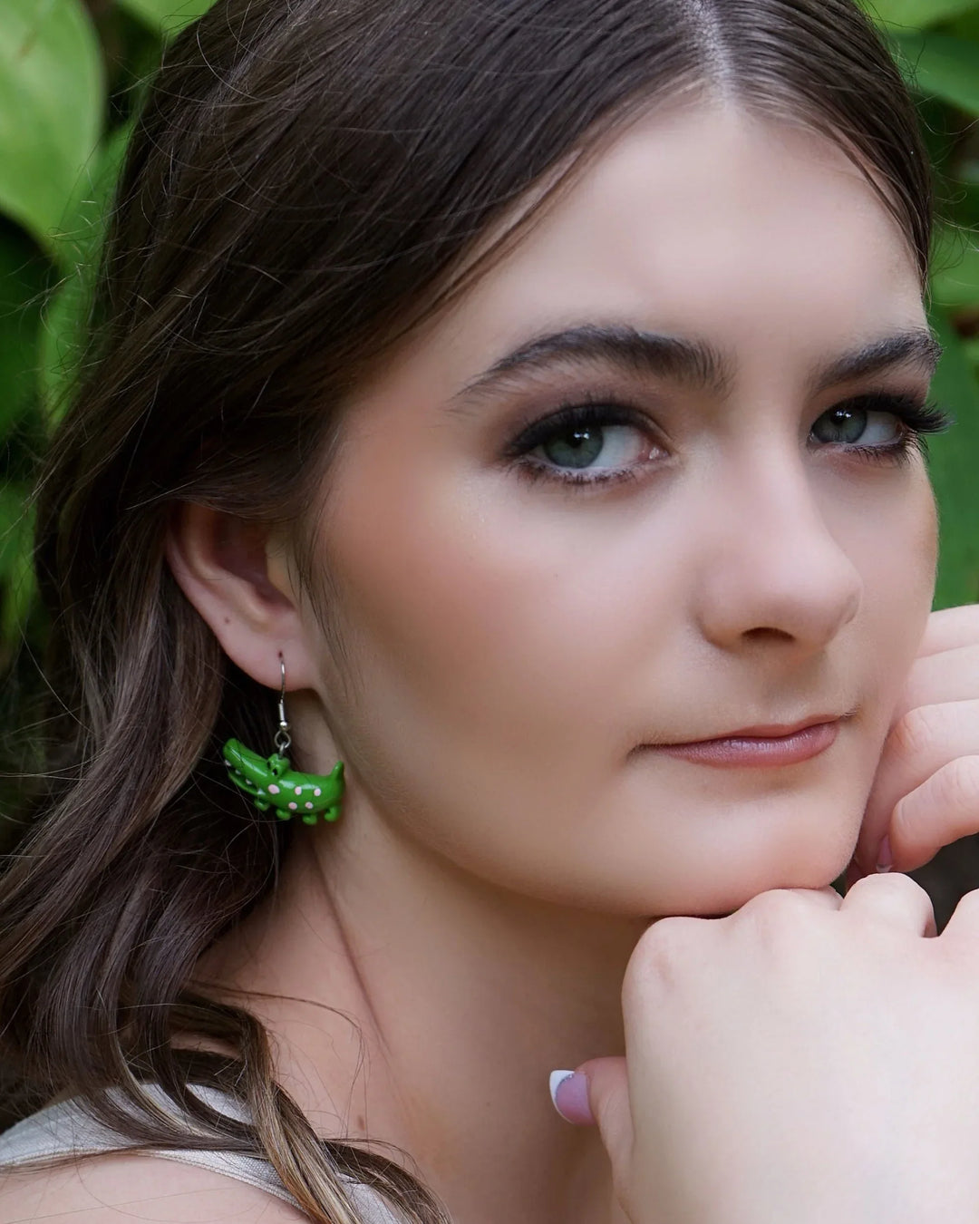 Side profile of model wearing cute green crocodile drop earrings with silver hooks.