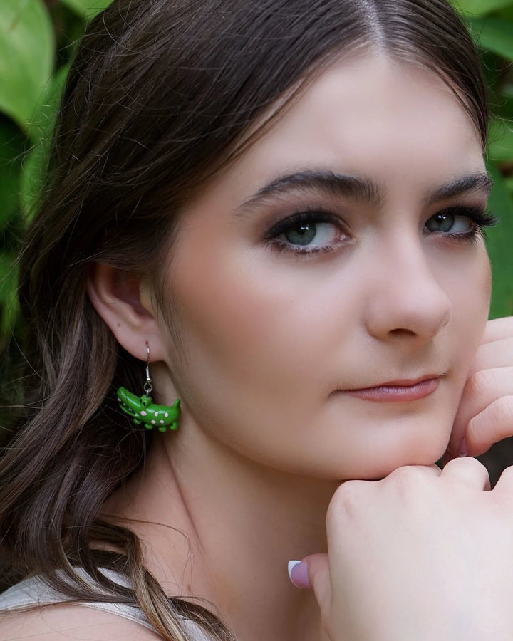 Side profile of model wearing cute green crocodile drop earrings with silver hooks.