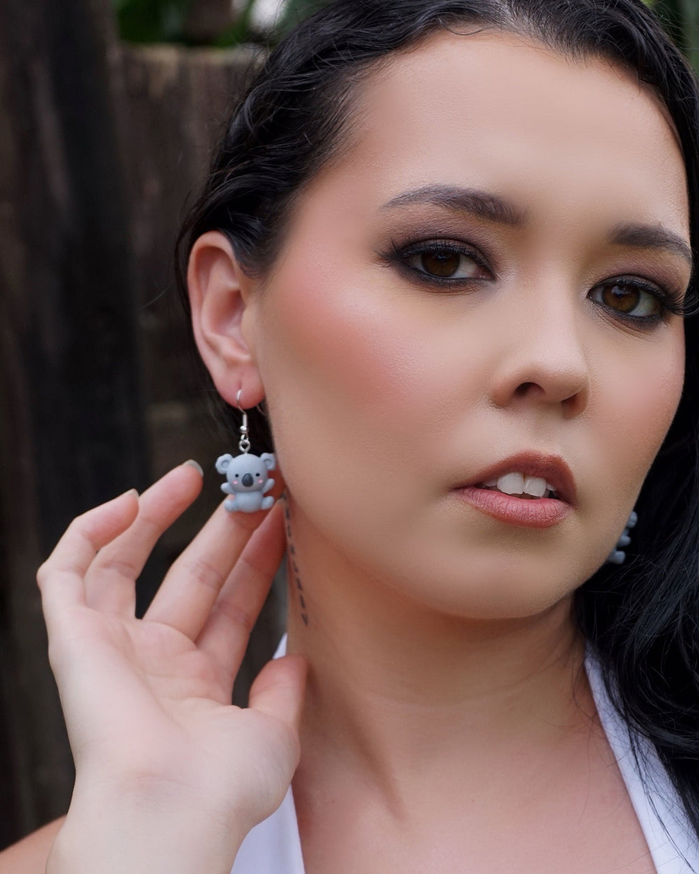 Model holding a cute grey koala dangle earring, showing size and detail of the Australiana animal design.