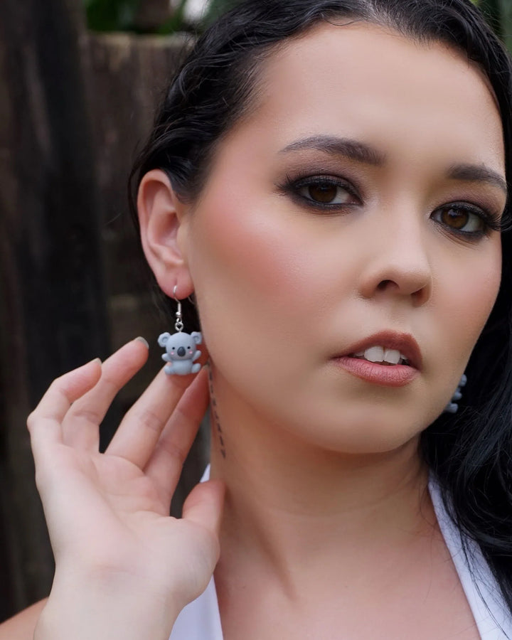 Model holding a cute grey koala dangle earring, showing size and detail of the Australiana animal design.