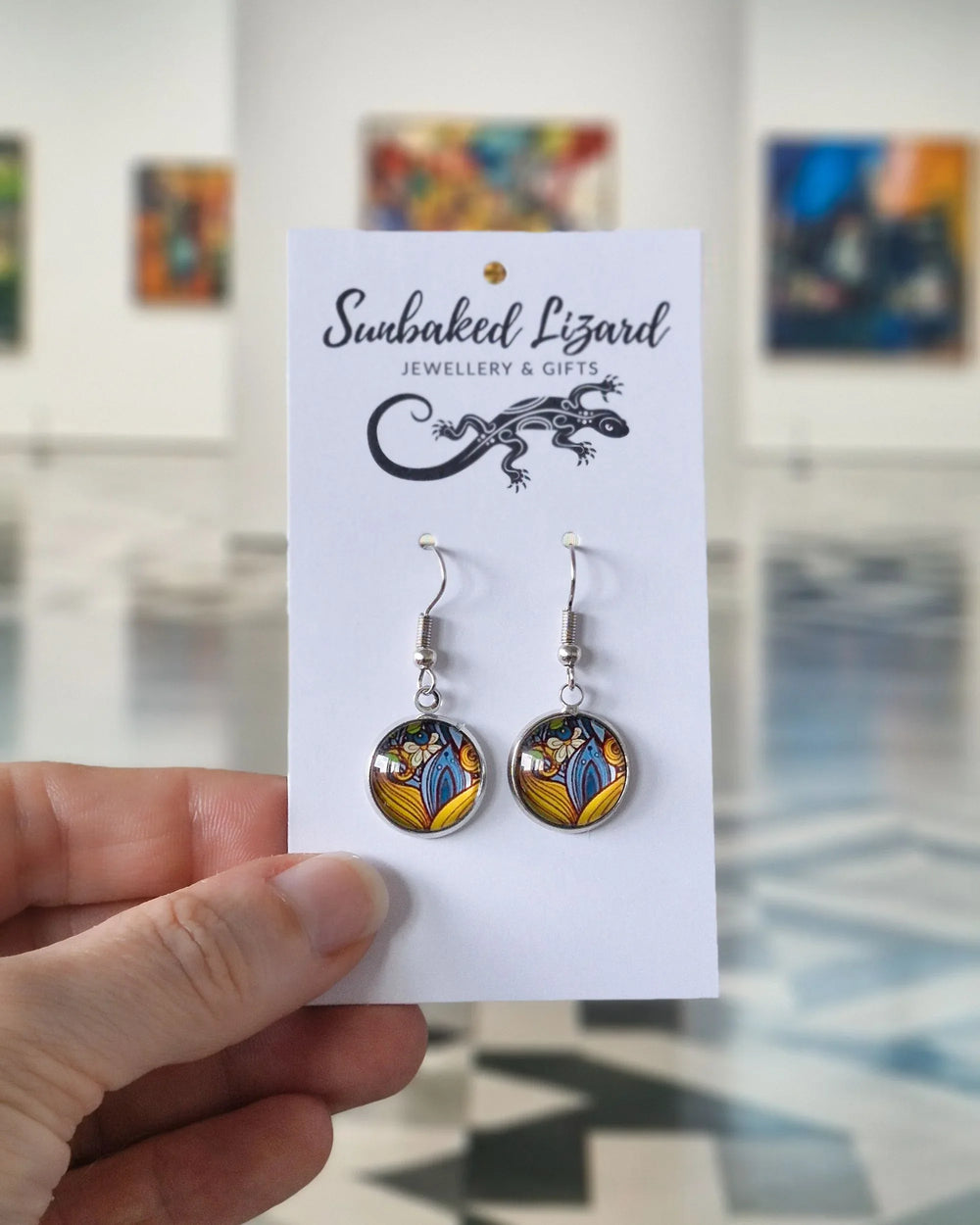 Patterned glass earrings displayed on Sunbaked Lizard jewellery card held in hand