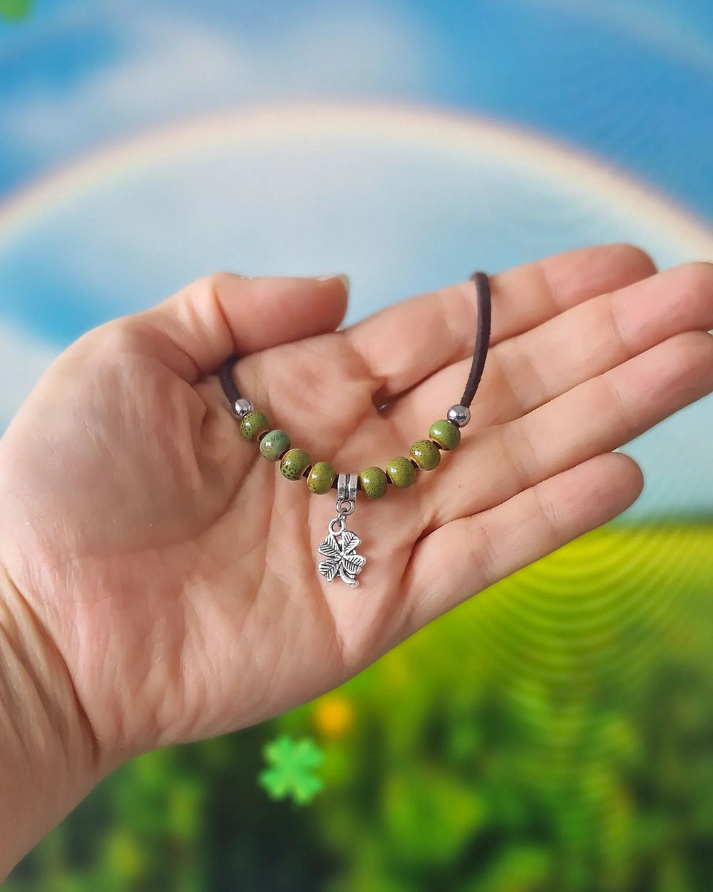 Shamrock charm bracelet held in hand showing green beads, silver shamrock charm and adjustable cord