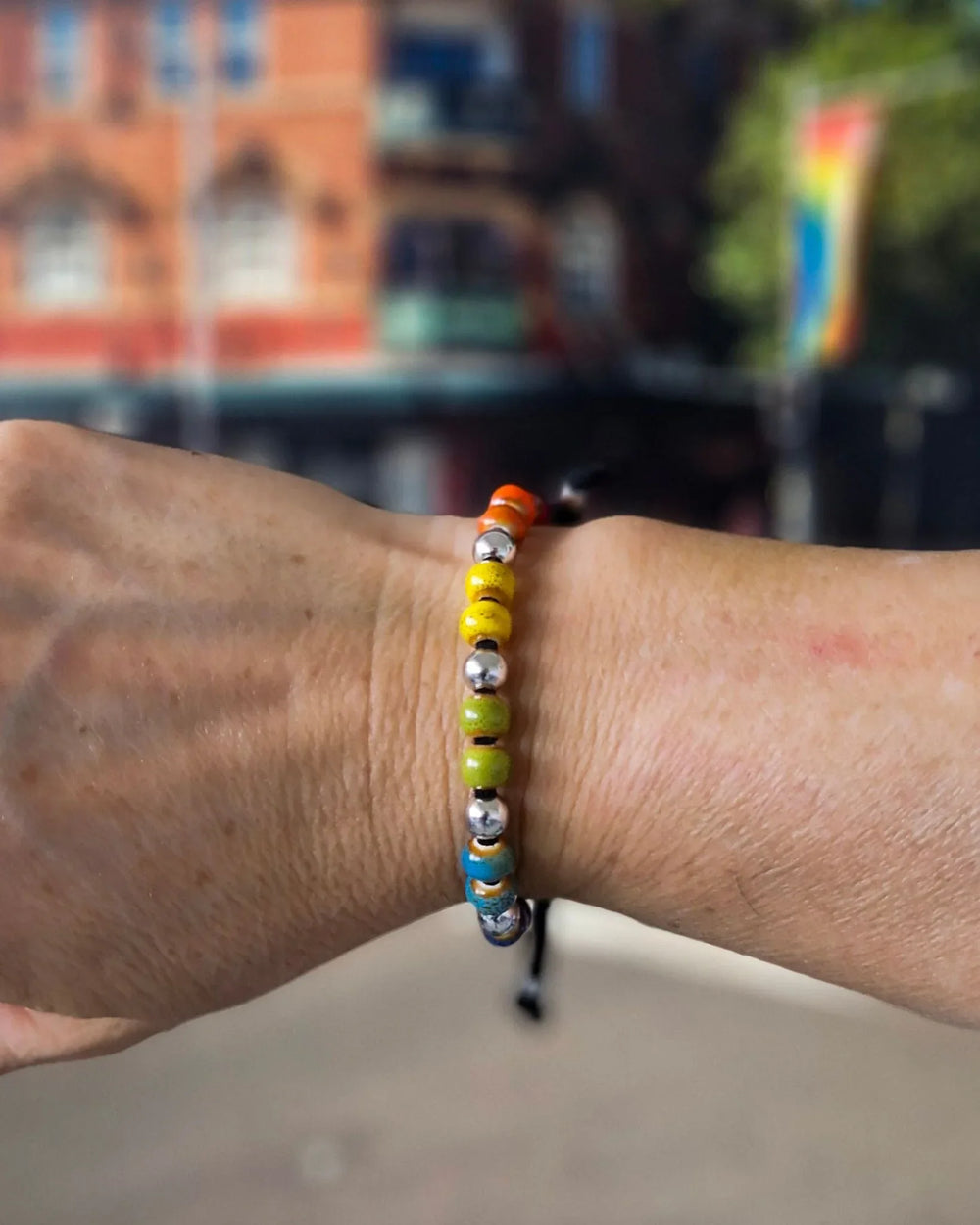 Person wearing Rainbow Pride bracelet with rainbow ceramic beads for Pride and Mardi Gras style