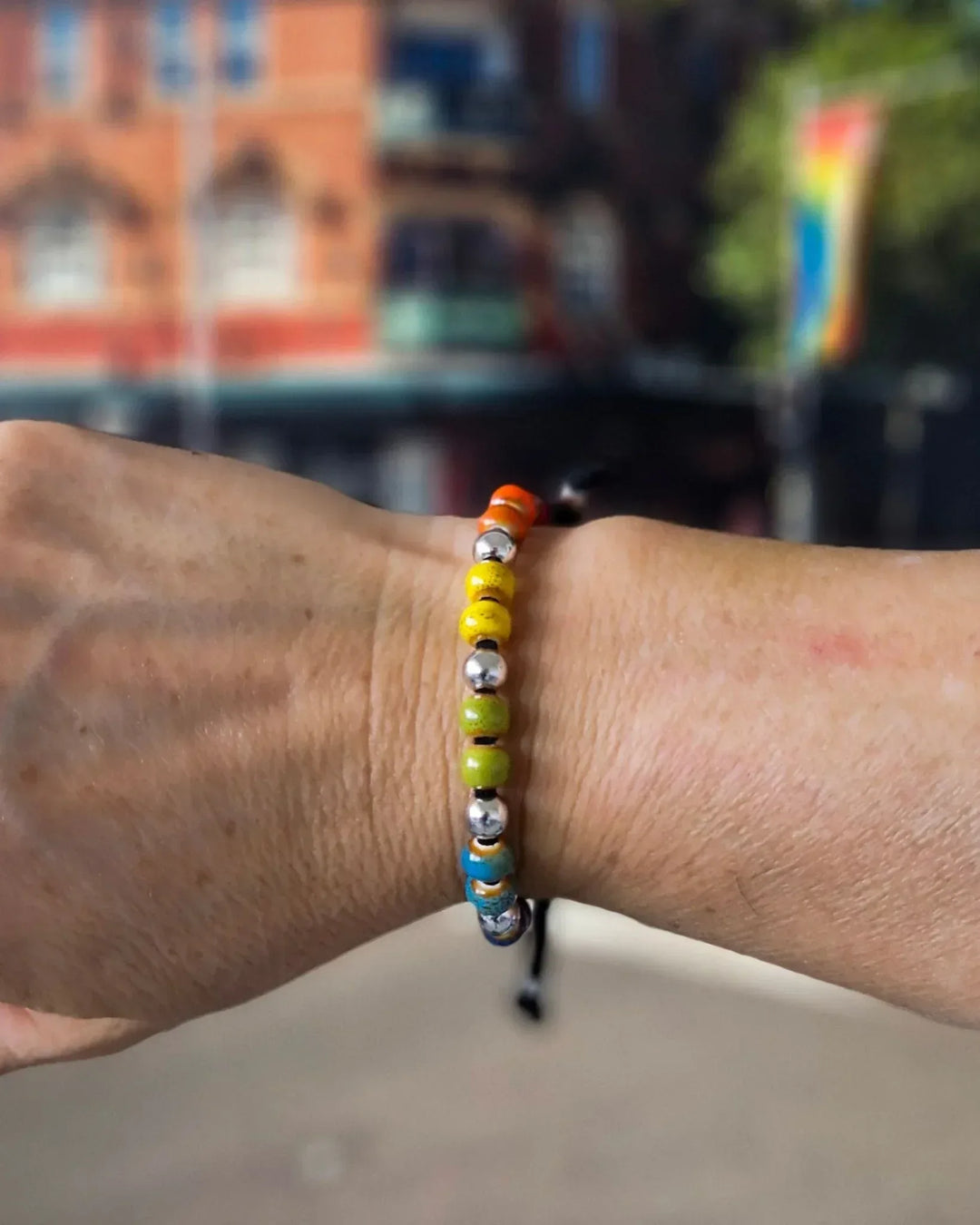 Person wearing Rainbow Pride bracelet with rainbow ceramic beads for Pride and Mardi Gras style