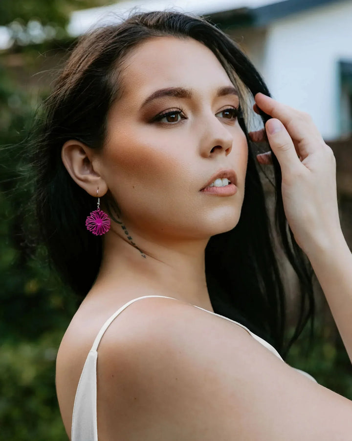 Model wearing pink filigree daisy drop earrings, showing size and movement when worn