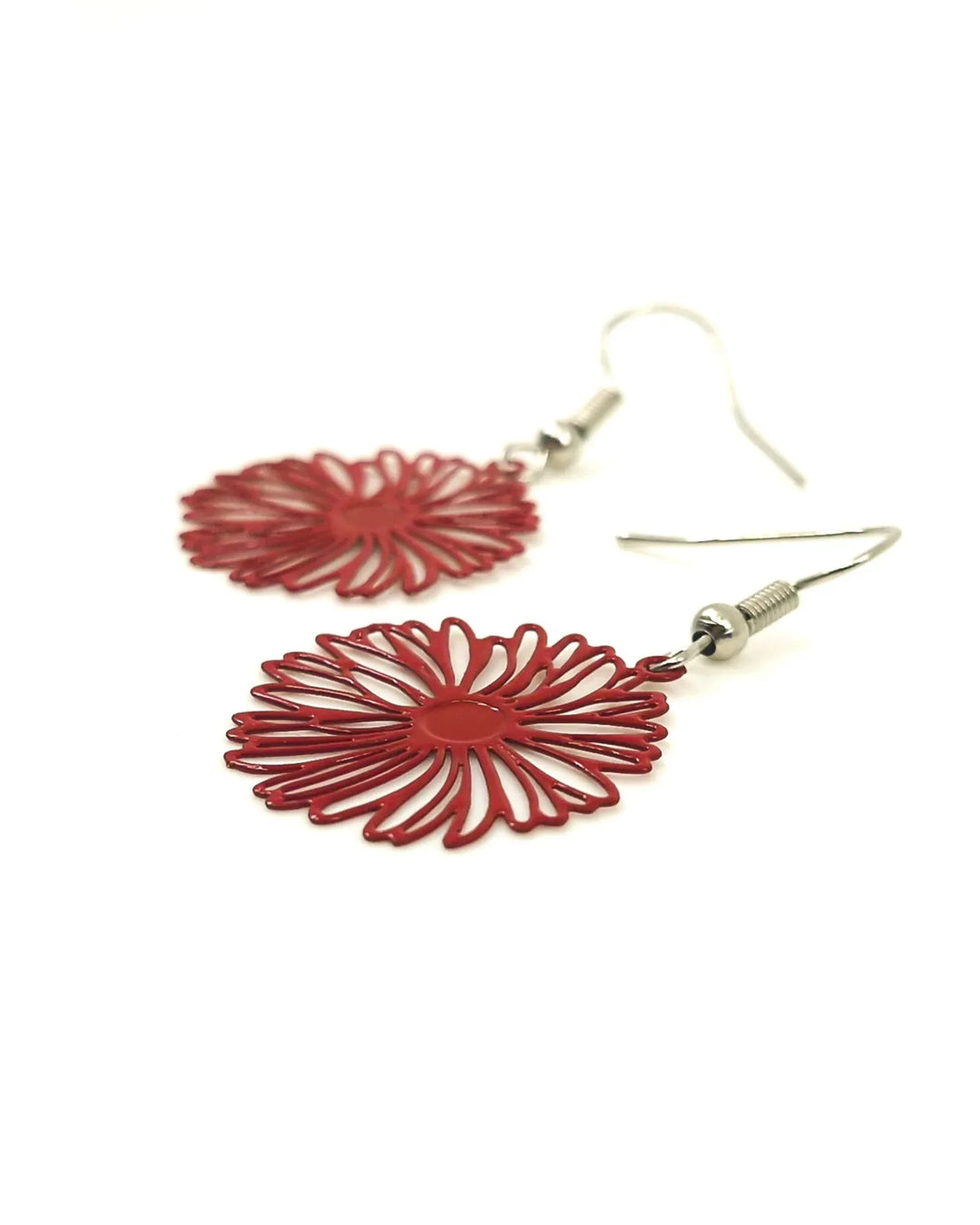 Angled close-up of red filigree daisy drop earrings showing delicate metal flower detail