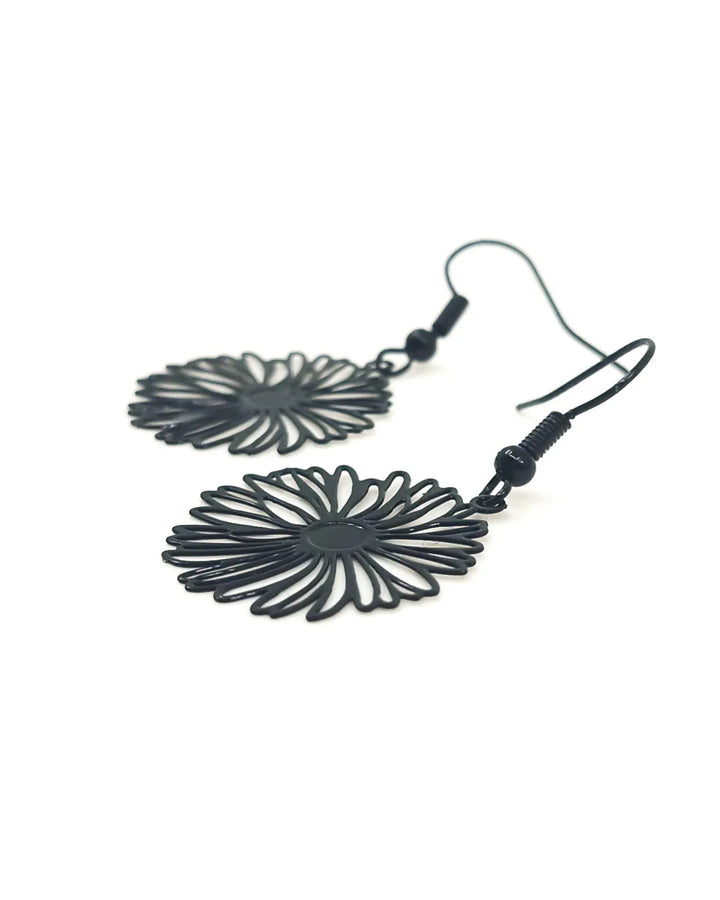 Angled close-up of black filigree daisy drop earrings highlighting lightweight metal flower design
