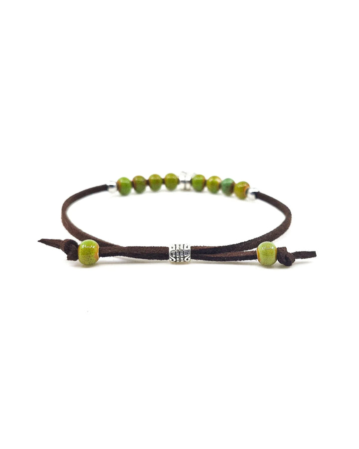 Detail view of shamrock bracelet highlighting adjustable brown cord and ceramic bead finish