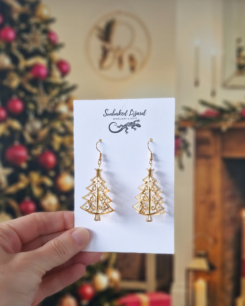 3D gold Christmas tree earrings on a Sunbaked Lizard backing card against a Christmas background