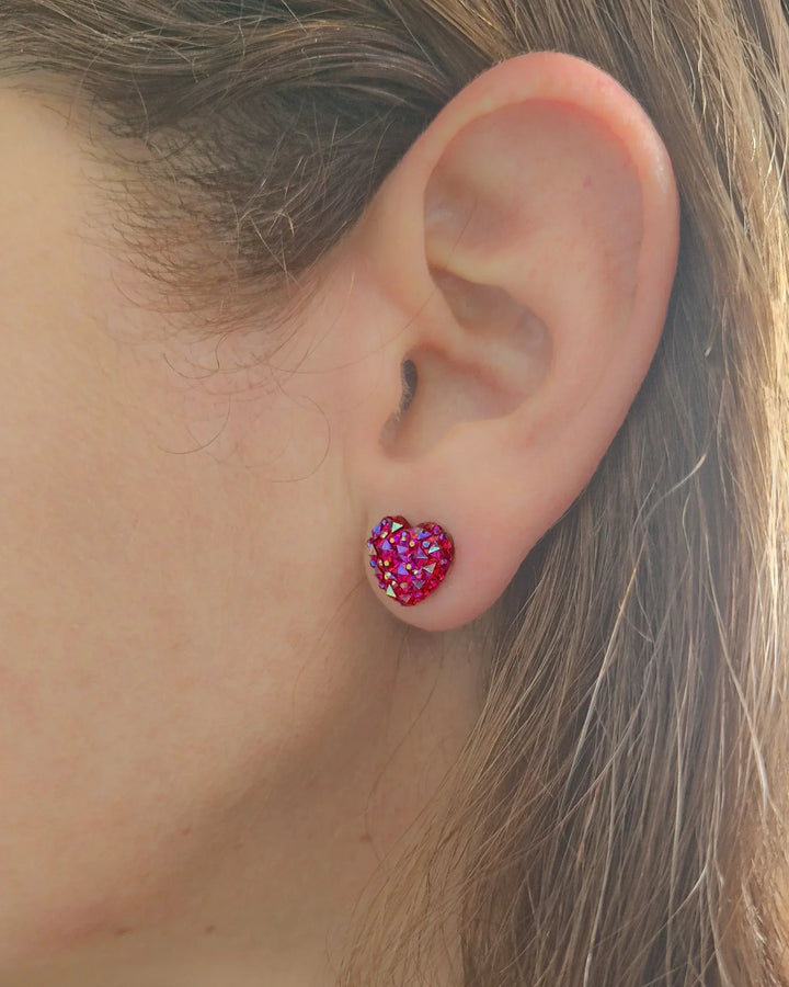 Close-up of model wearing a red sparkly heart shaped earrings in hot pink