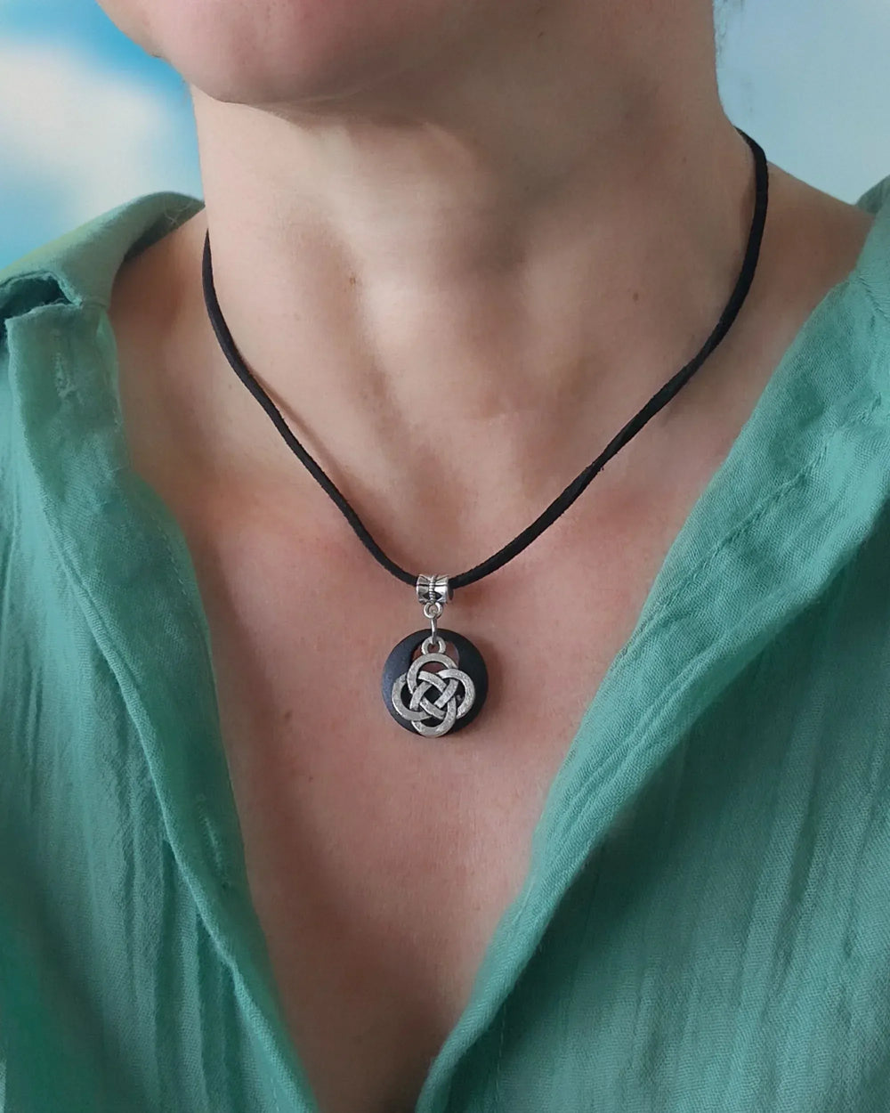 Celtic knot necklace worn on model, showing pendant size and length on black cord against green top
