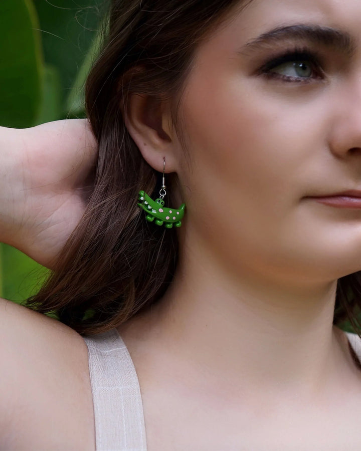 Model holding a cute green crocodile drop earring, showing size and detail of the Australiana animal design.