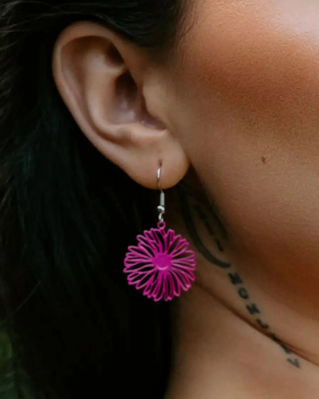 Close-up of filigree daisy drop earring worn on ear, showing size and drop length