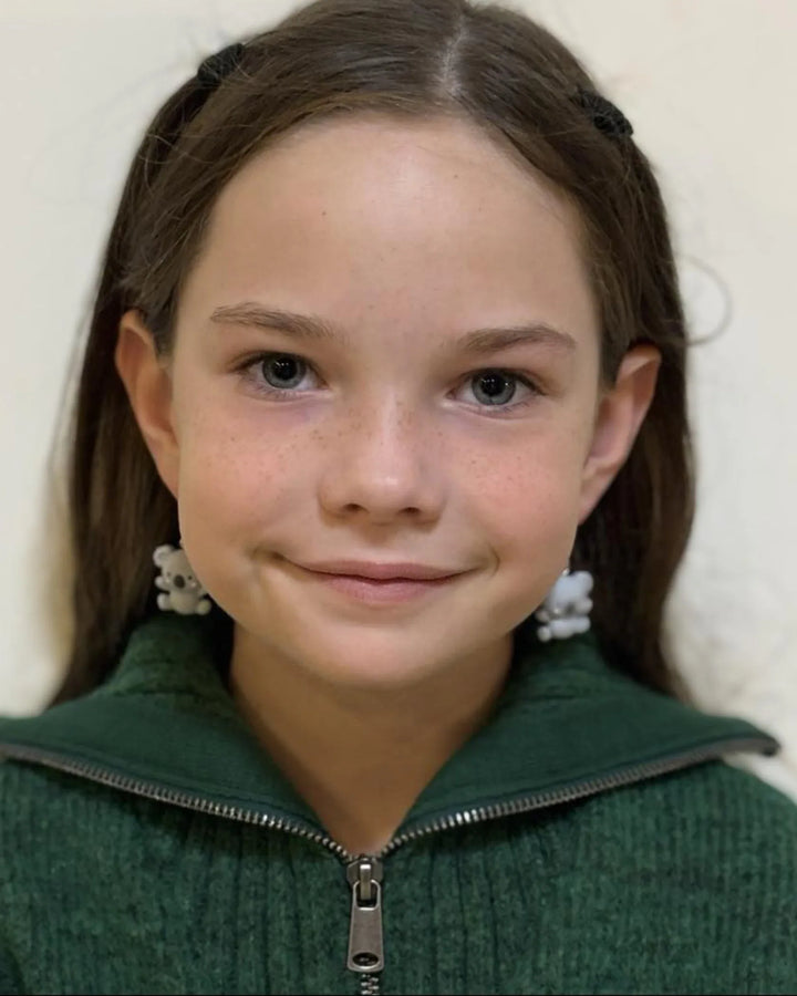 Child wearing cute grey koala dangle earrings, showing playful Australiana animal jewellery on both ears.