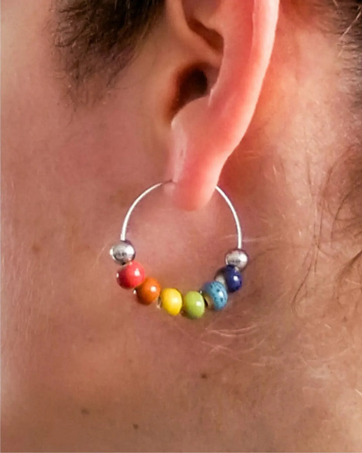 Model wearing Rainbow Pride hoop earrings with rainbow ceramic beads for Pride and Mardi Gras