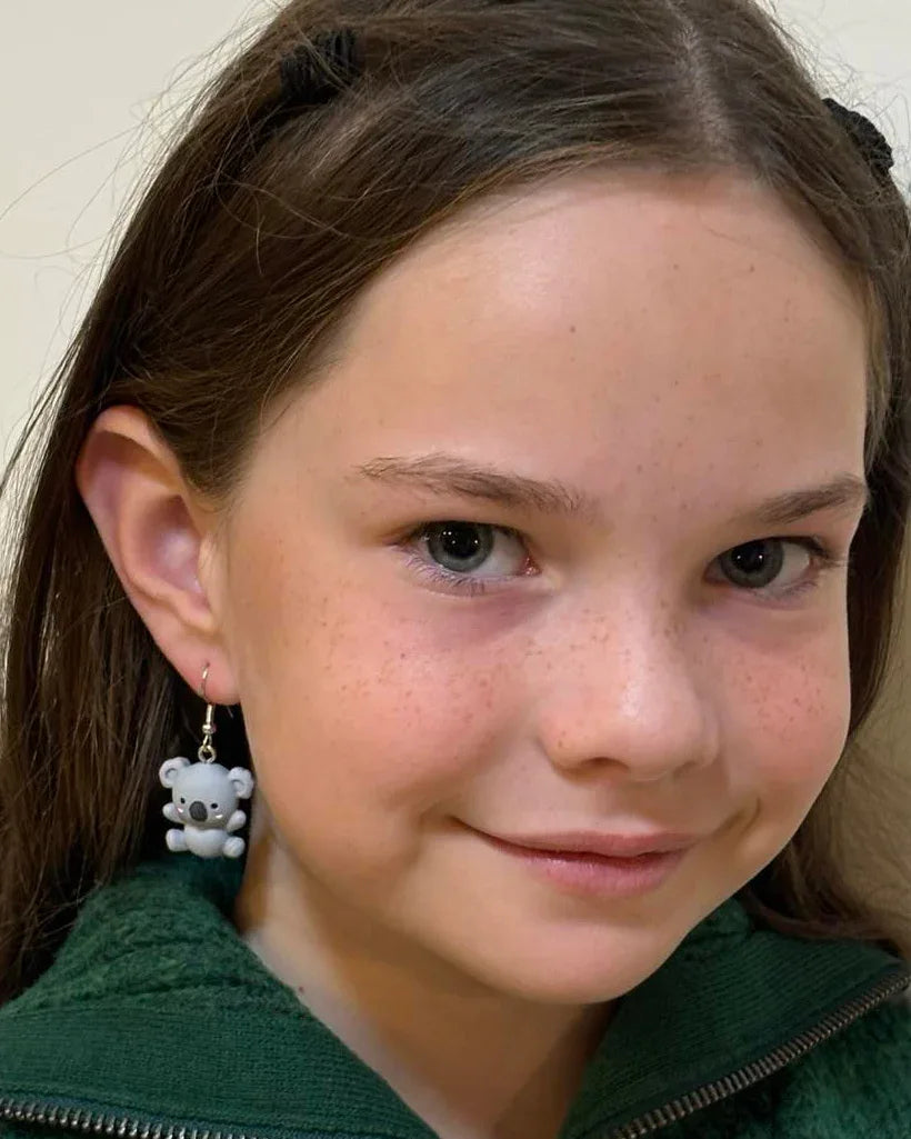 Side profile of model wearing cute grey koala dangle earrings with silver hooks.