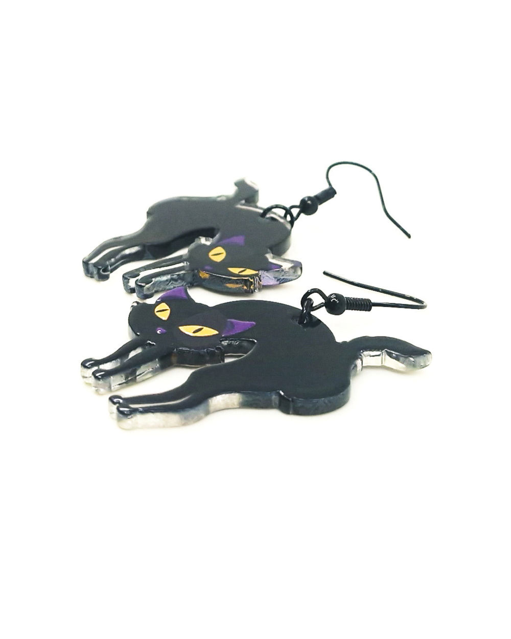 Angled view of black cat Halloween earrings showing glossy finish, purple ears and yellow eyes