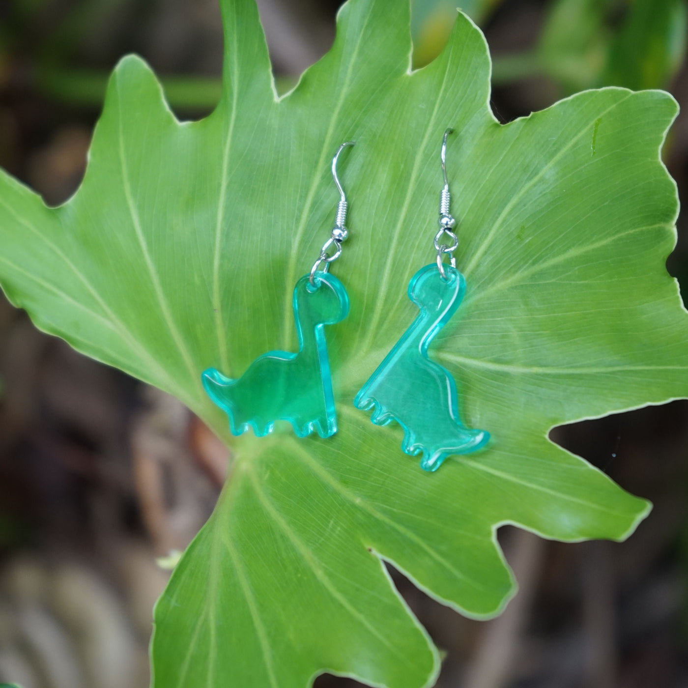 Blue Dino The Dinosaur Dangles resting on a large green leaf