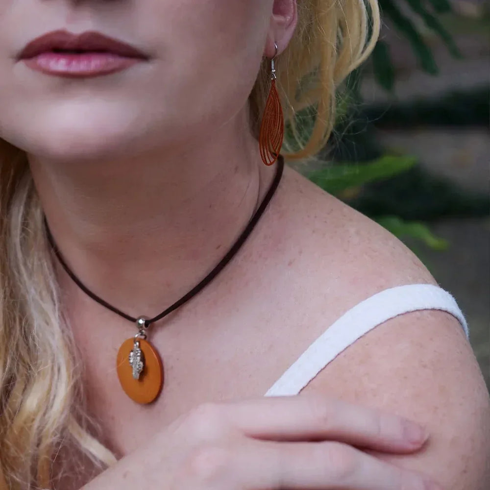 Close-up of a person wearing an timber cactus pendant necklace with a blurred background