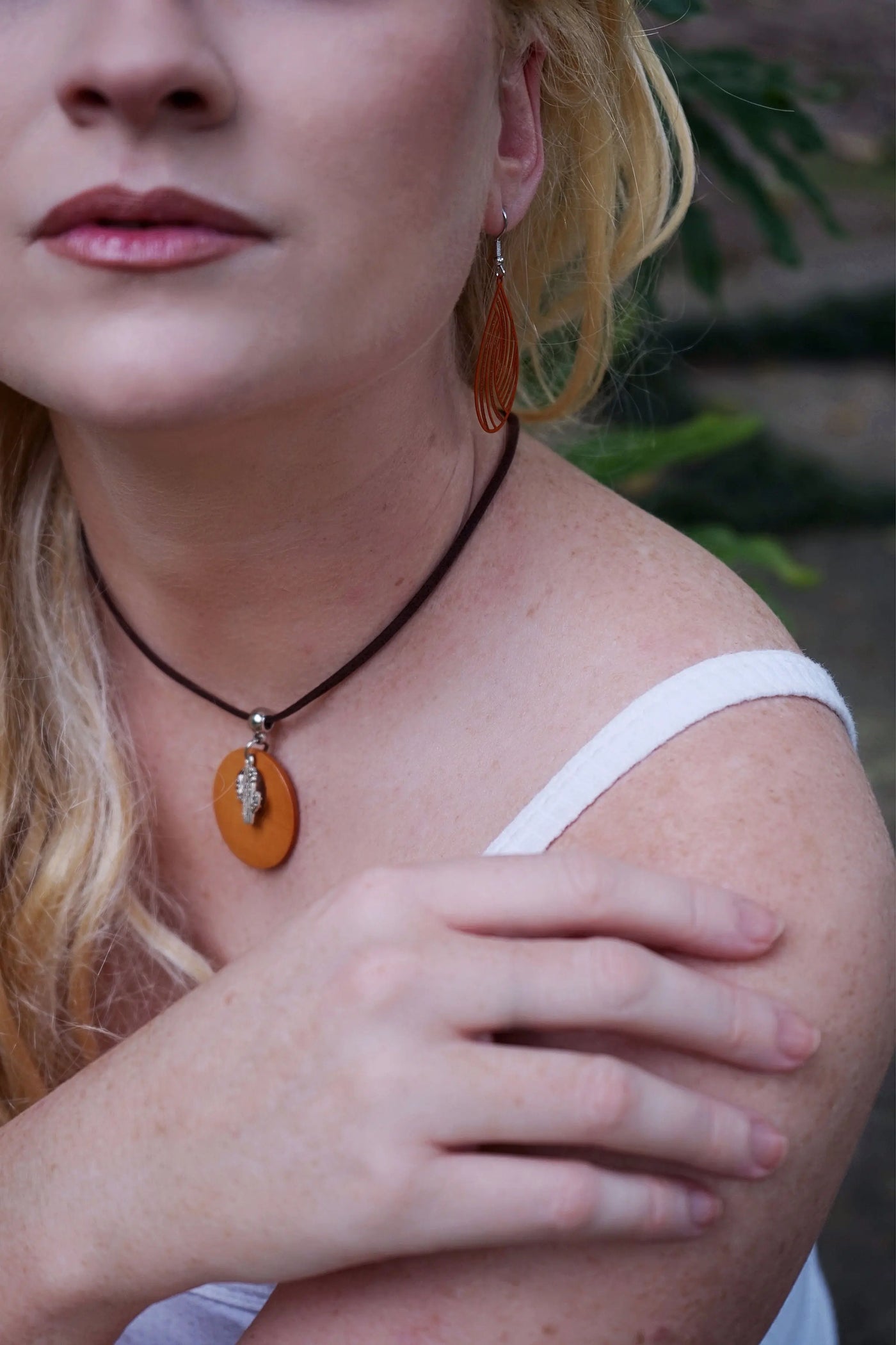 Close-up of a person wearing an timber cactus pendant necklace with a blurred background