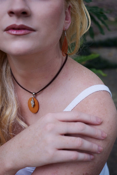 Close-up of a person wearing an timber cactus pendant necklace with a blurred background