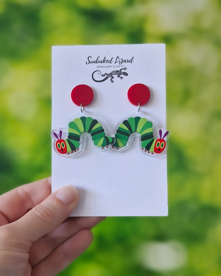 Hand holding Caterpillar Drops - Unique Nature-Inspired Earrings on a Sunbaked Lizard Jewellery &amp; Gifts backing card showing scale