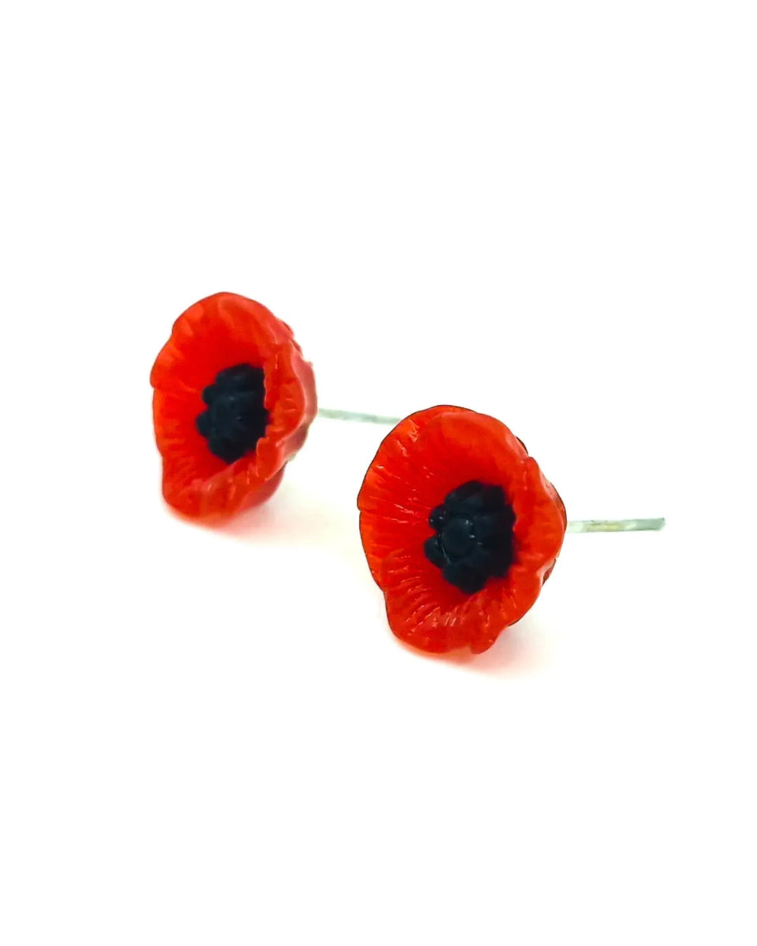 Detail view of red poppy flower earrings on a white background