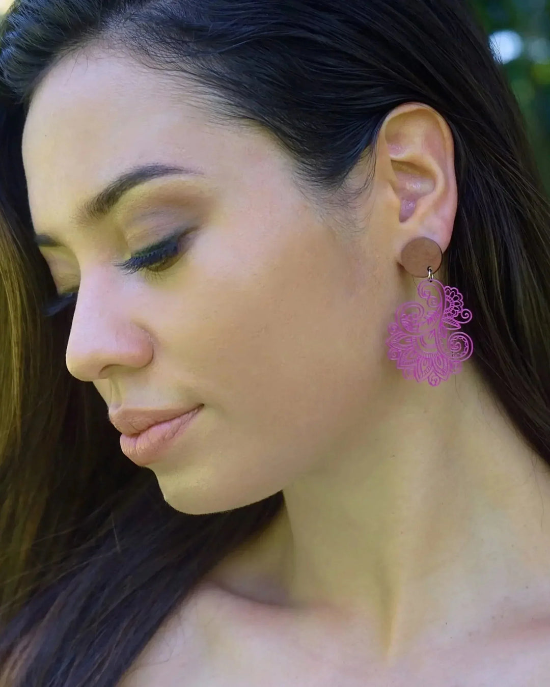 Woman modelling vibrant pink filigree statement earrings with wooden stud tops and detailed lace style cutwork design.