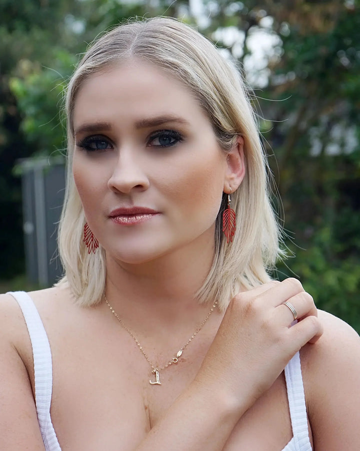 Model wearing red filigree leaf drop earrings showing size and lightweight leaf shape