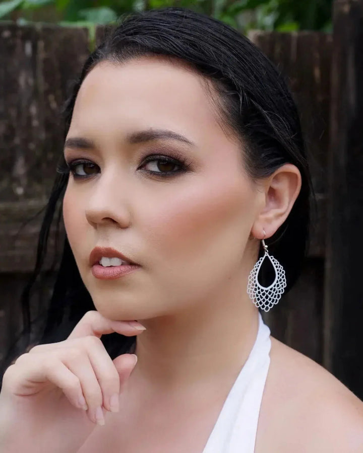 Model wearing filigree teardrop dangle earrings showing long drop length and delicate scalloped cut-out design
