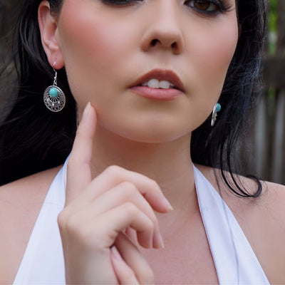 Close up view from the front of woman wearing silver earrings with a blurred background