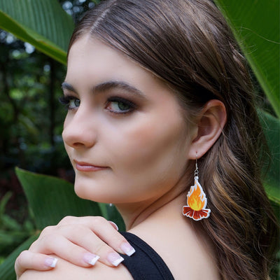 Woman wearing a campfire earring with big leaves in the background