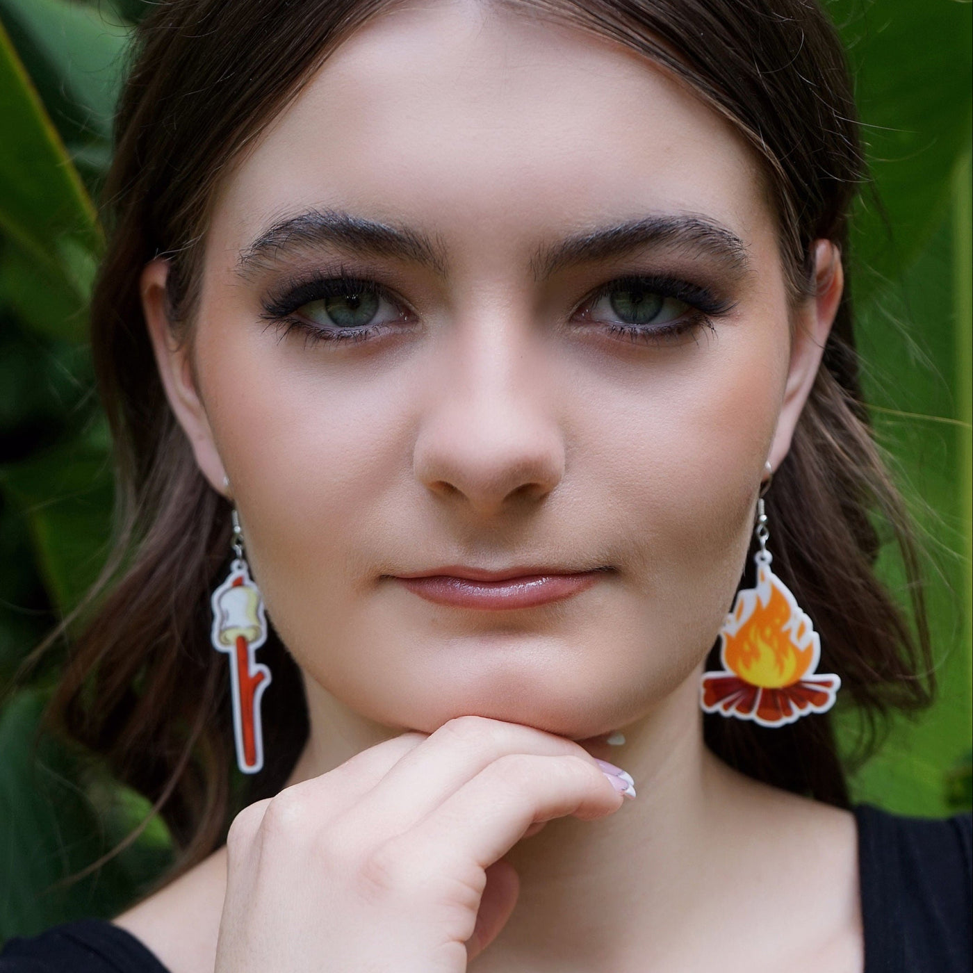 Woman wearing large novelty campfire earrings with a natural background