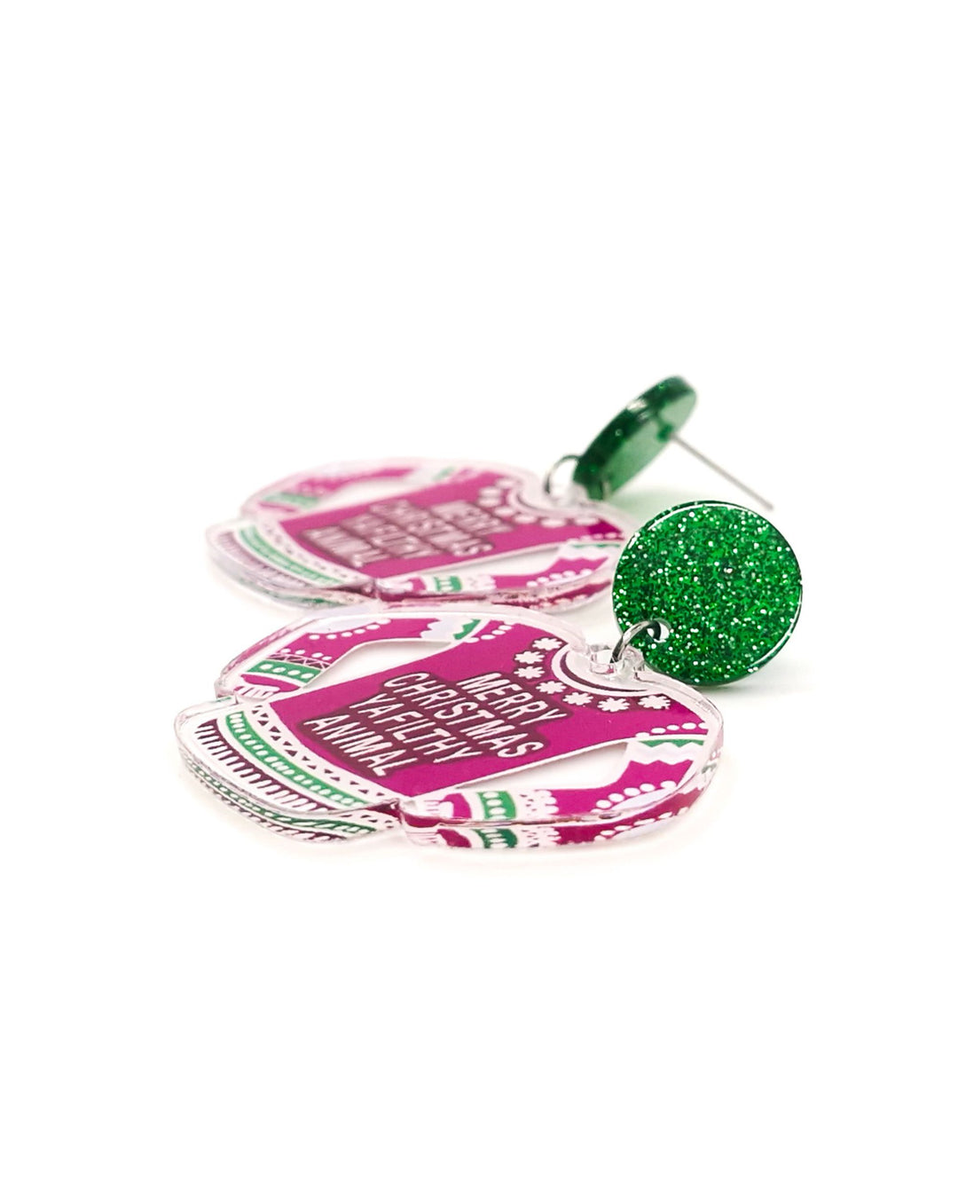 Detail photo of earrings shaped like pink Christmas sweaters with text on a white background