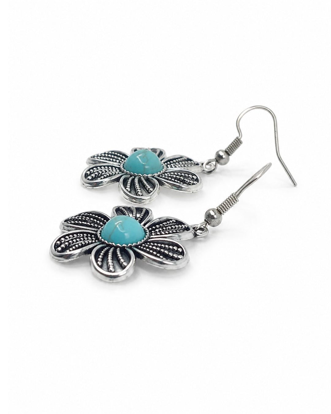 A pair of silver-toned dangle earrings shaped like flowers, featuring textured silver petals and a central turquoise-colored stone, shown on a plain white background.