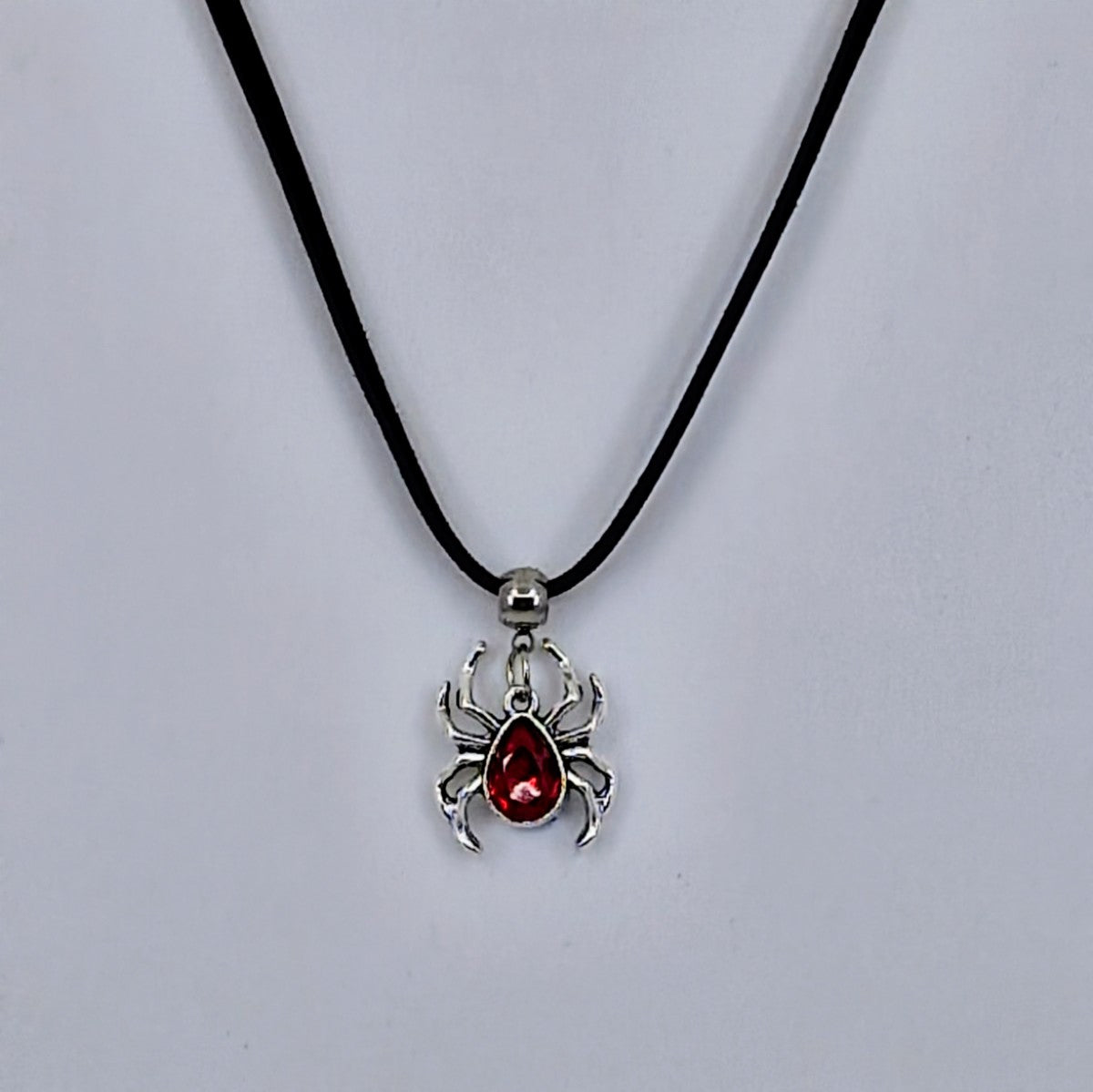 Silver spider pendant necklace with ruby-red gem-style body on black cord – creepy-cute Halloween jewellery