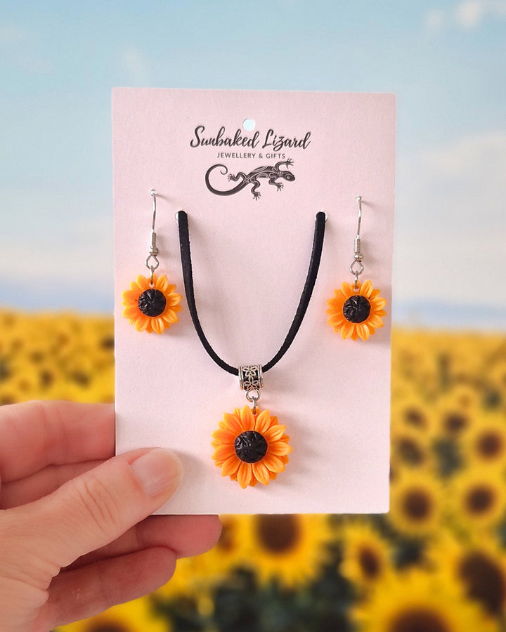 Yellow Sunflower necklace and matching drop earrings set on Sunbaked Lizard card with a sunflower field background