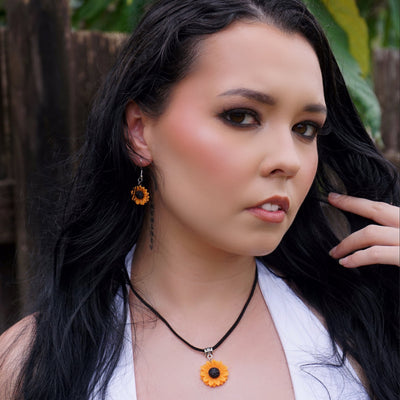 Woman with long dark hair wearing sunflower pendant earrings