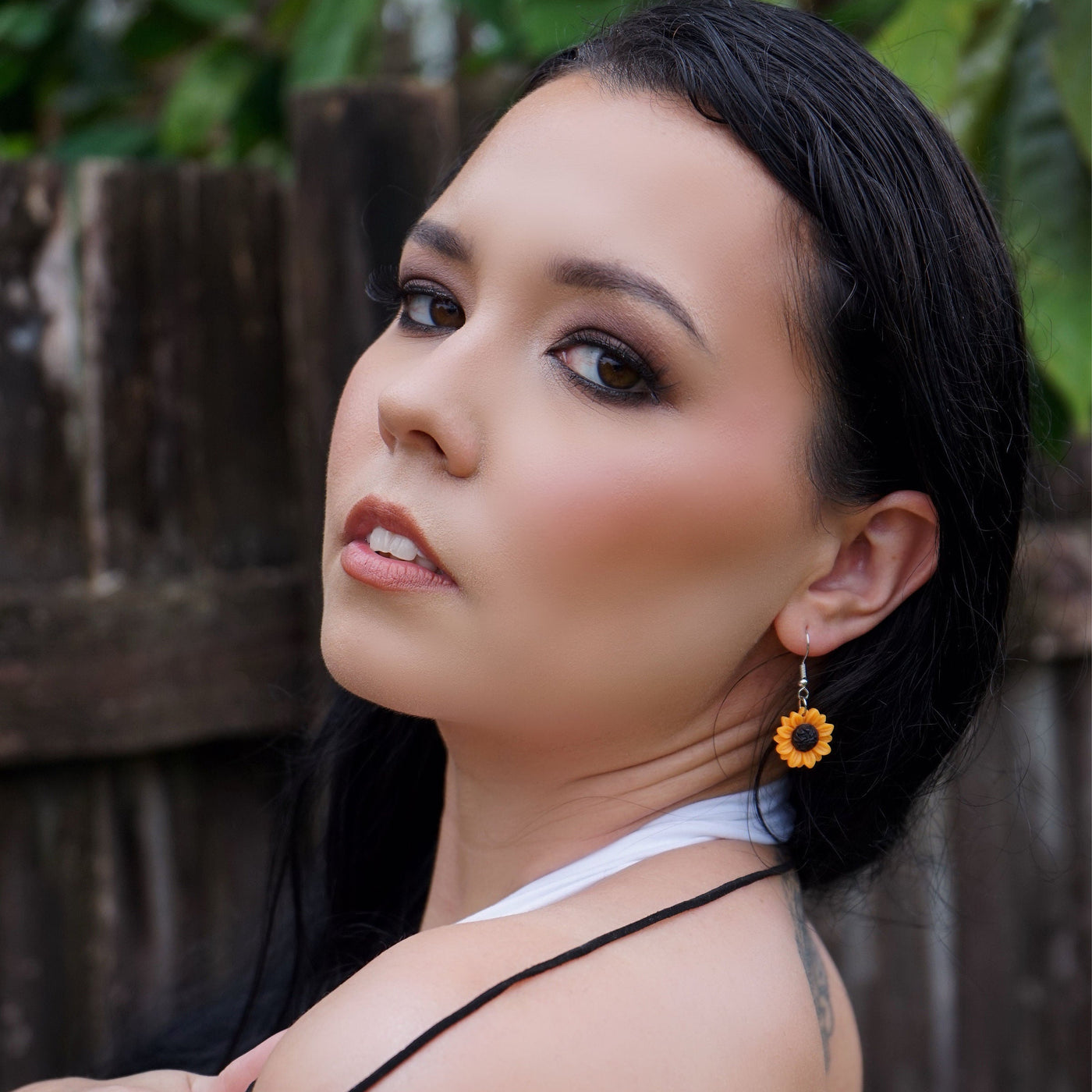 Woman wearing sunflower-themed jewelry against a natural background