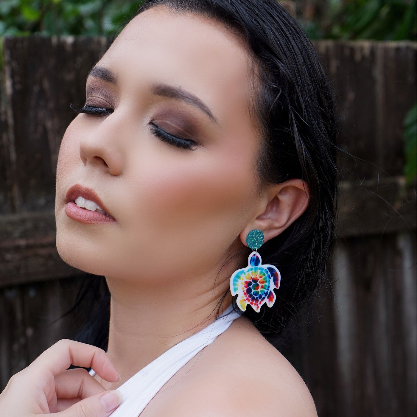 Woman wearing colorful turtle earrings with a blurred natural background