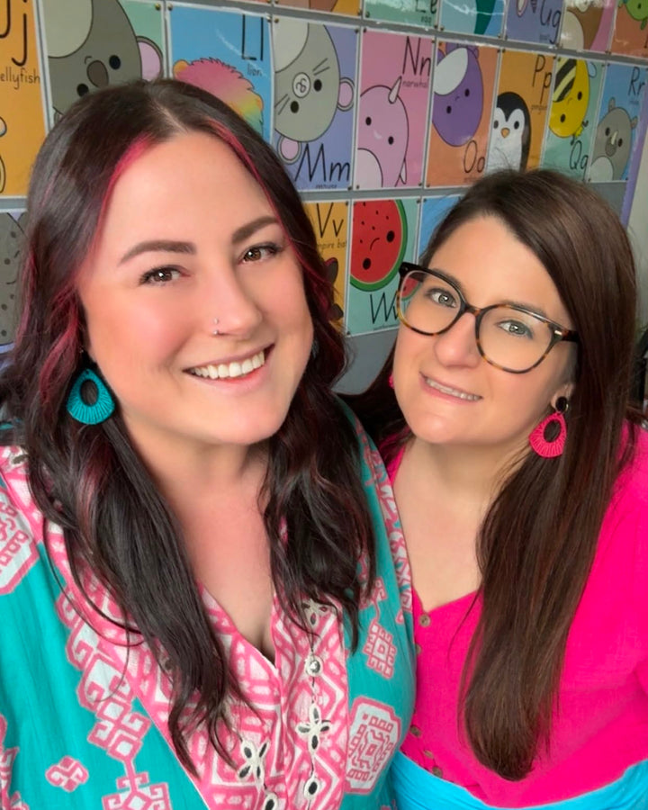 Two people wearing Acrylic Woven Earrings in teal and pink, styled with bright colourful outfits in a classroom setting.
