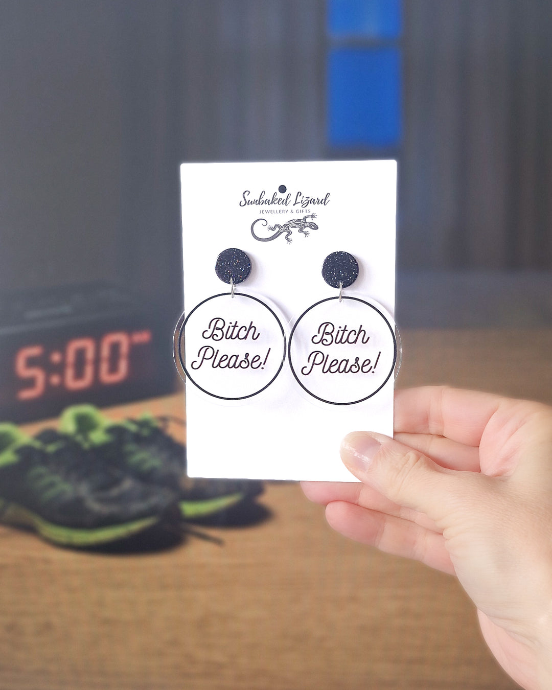 Bitch Please black acrylic statement earrings displayed on a Sunbaked Lizard card in a lifestyle setting.
