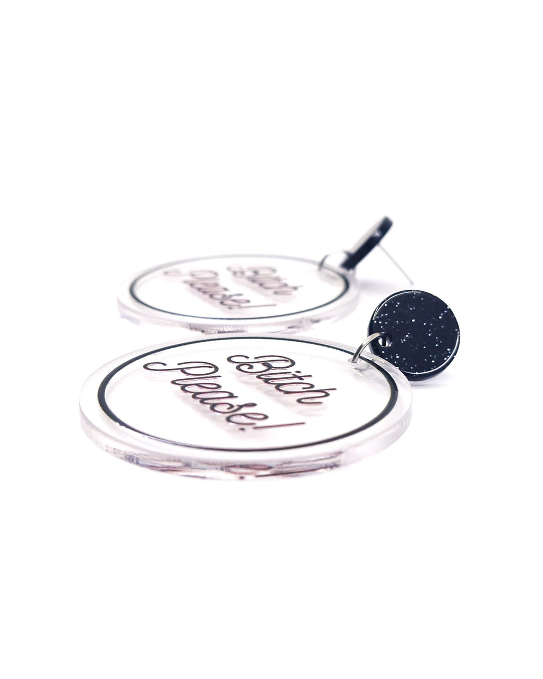 Close-up of Bitch Please acrylic statement earrings with black script, clear round charms and glitter black studs.