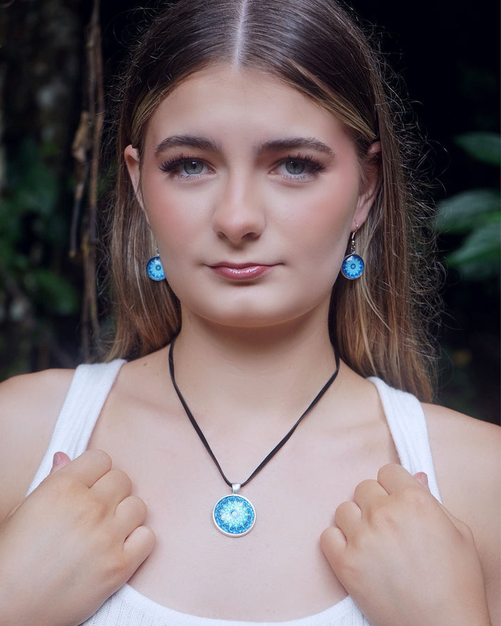 Model wearing Blue Mandala earrings and necklace featuring a vibrant blue glass cabochon in a silver-toned setting