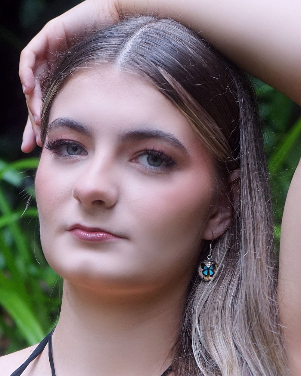 Close-up of blue Ulysses butterfly earrings worn by model