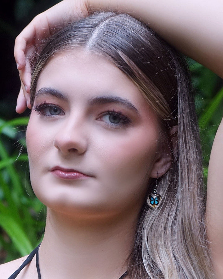 Close-up of blue Ulysses butterfly earrings worn by model
