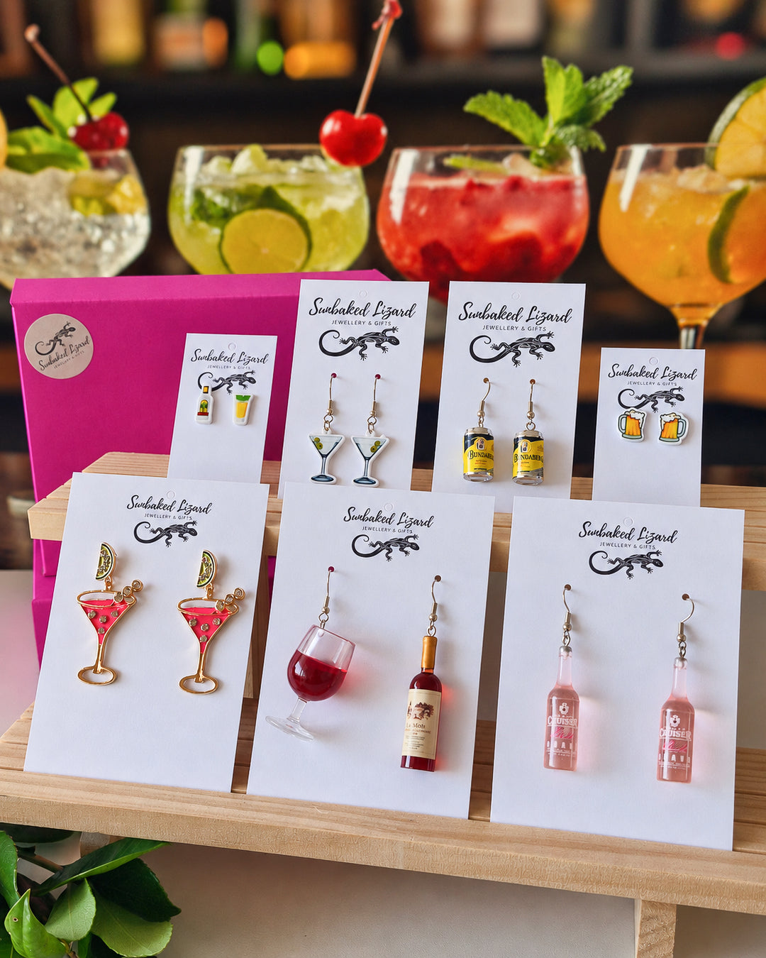 Booze Earrings Gift Box earrings on Sunbaked Lizard cards on a bar, with real cocktails behind