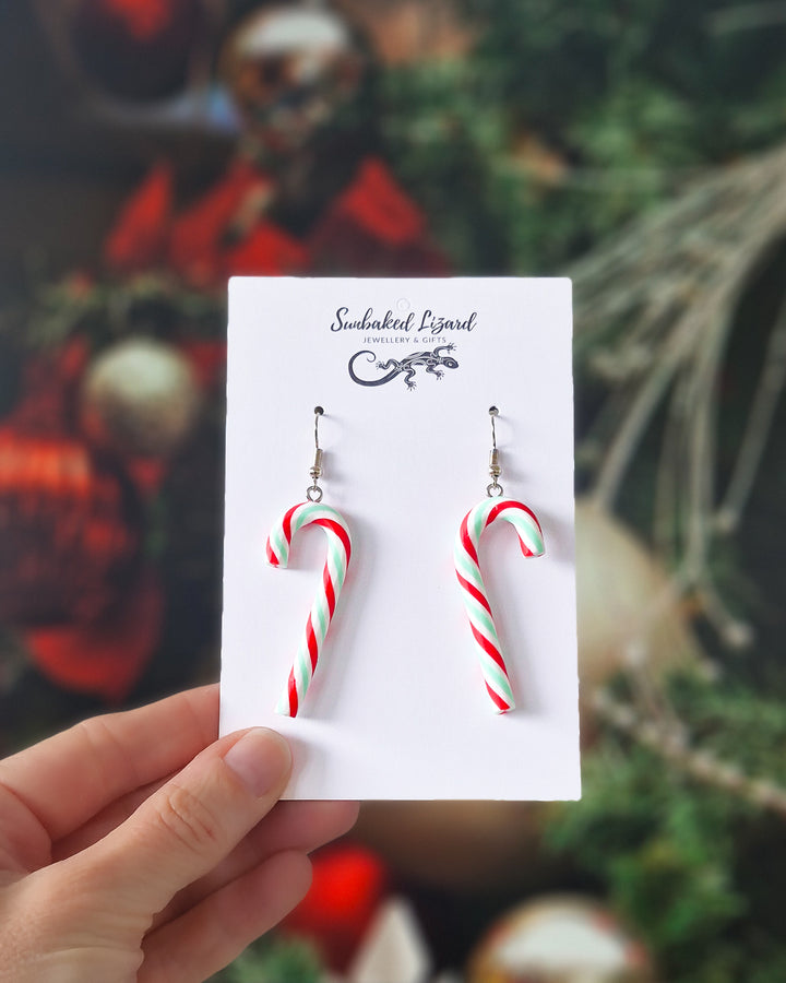 Candy cane Christmas earrings on a Sunbaked Lizard backing card against a Christmas background